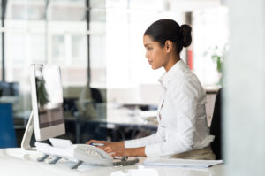 Mulher na recepção de uma clínica digitando no computador